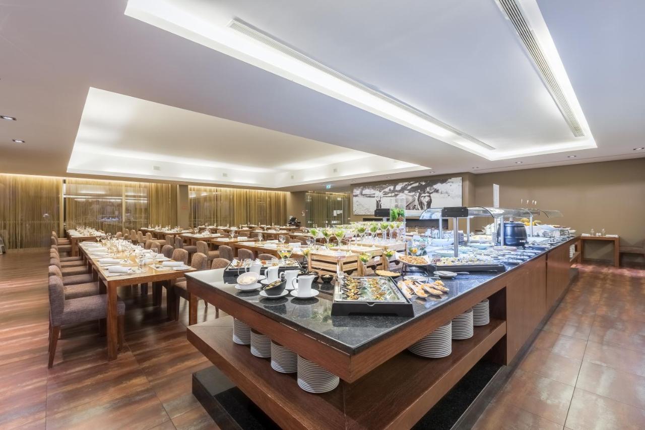 Ap Lago Montargil - Conference & Spa Dış mekan fotoğraf The photo displays a spacious restaurant interior, featuring a well-organized dining area with multiple tables set for patrons. In the center, there is a large buffet station filled with an array of food items. The decor is modern and elegant, with w