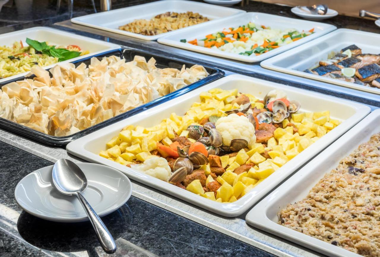 Ap Lago Montargil - Conference & Spa Dış mekan fotoğraf The photo shows a buffet-style display of various dishes. There are several rectangular trays filled with different types of food. 

1. One tray contains a mix of vegetables and seafood, likely including potatoes and cauliflower.
2. Another tray hold