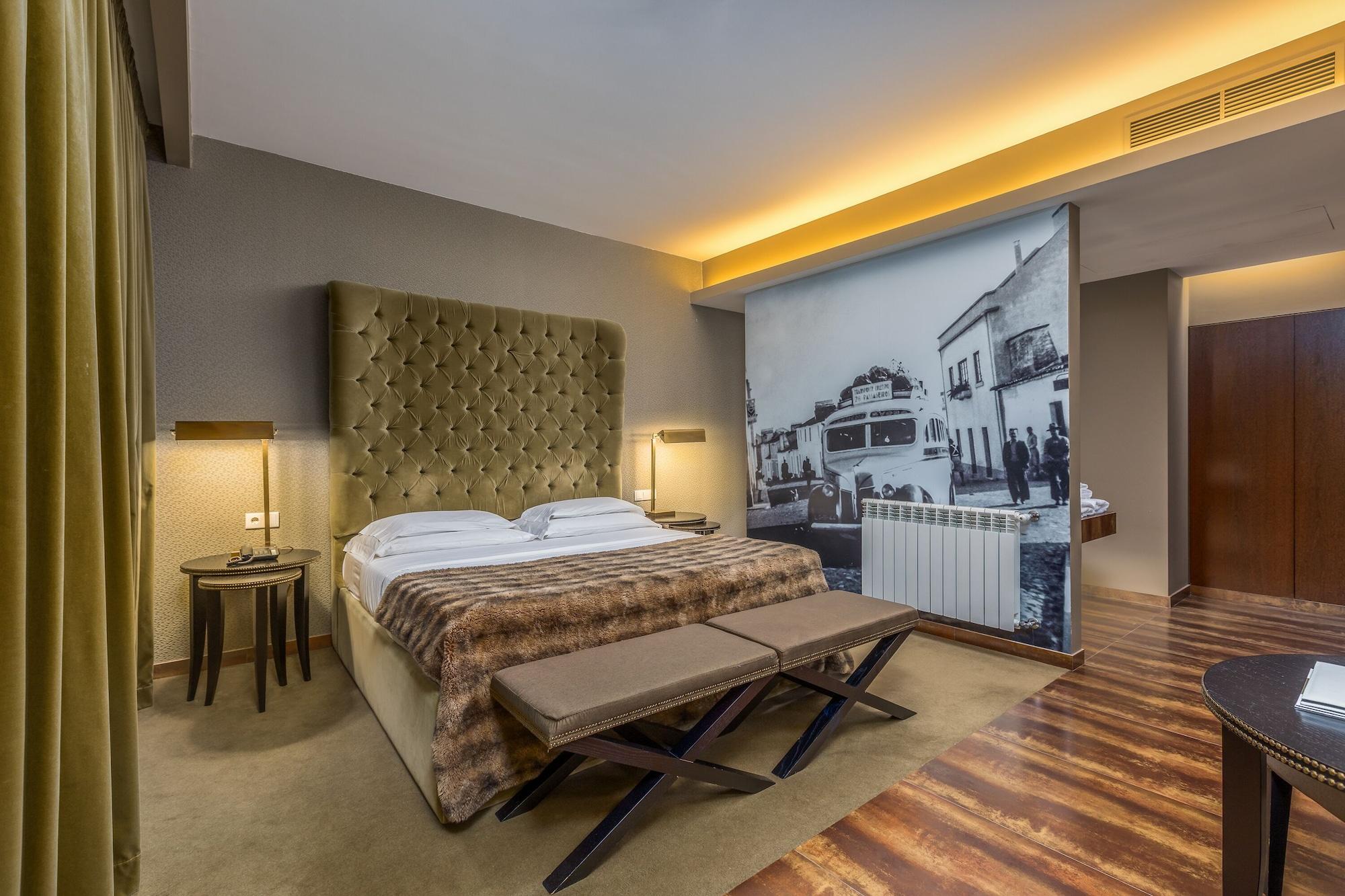 Ap Lago Montargil - Conference & Spa Dış mekan fotoğraf The photo shows a modern hotel room featuring a king-sized bed with a tufted headboard, dressed in white linens and a decorative throw blanket. On either side of the bed, there are bedside tables with lamps. The room is well-lit, with an ambient ceil