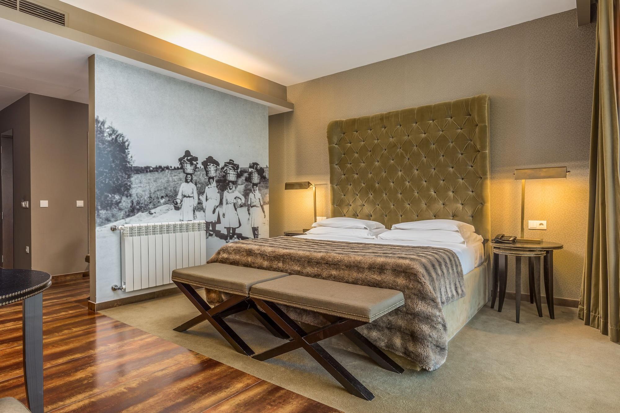 Ap Lago Montargil - Conference & Spa Dış mekan fotoğraf The photo shows a modern hotel room with a large, plush bed that has a tufted, green headboard. The bedding is white with a textured blanket at the foot of the bed. A decorative wall behind the bed features a black and white mural of children in a fi