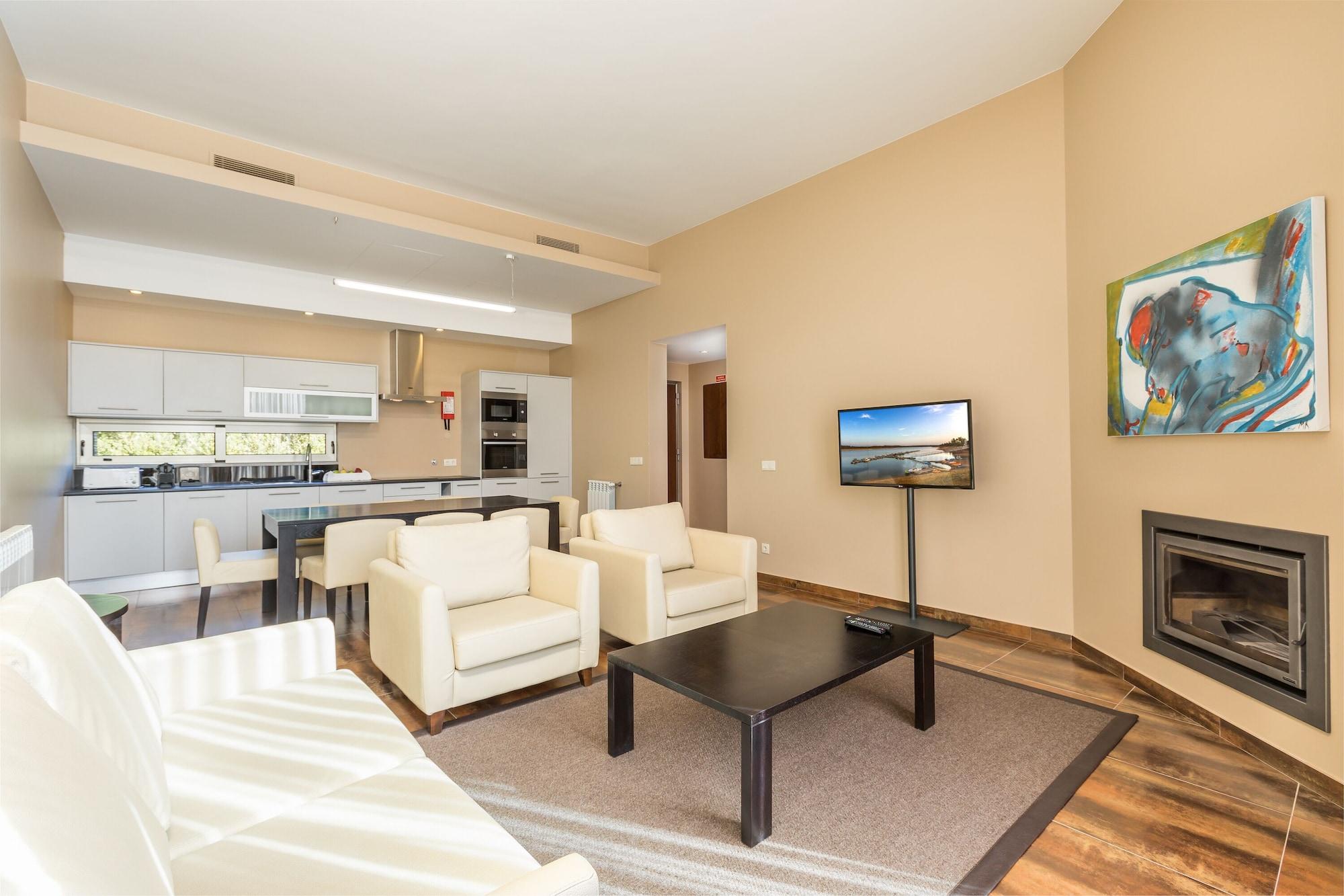 Ap Lago Montargil - Conference & Spa Dış mekan fotoğraf The photo shows a modern, spacious living area with a contemporary design. The room features light-colored walls and wooden flooring. 

In the center, there is a black coffee table surrounded by four white armchairs. A flat-screen TV is mounted on th